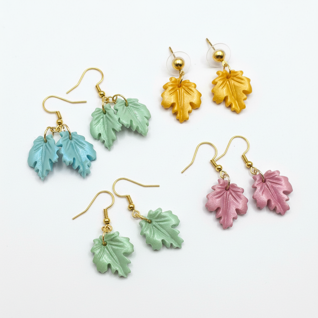 Polymer clay leaf earrings in various colors on white background