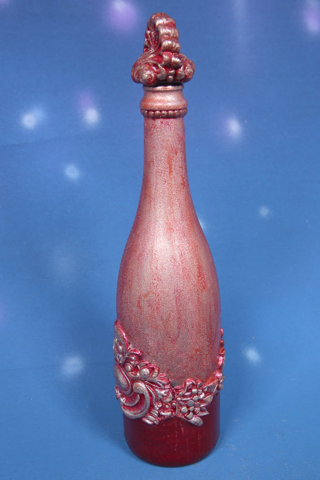 Decorated wine bottle with pink cracks and baroque ornaments